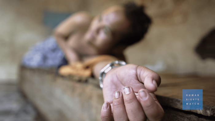 A man with psychological disability appears to be chained to a wooden bed.