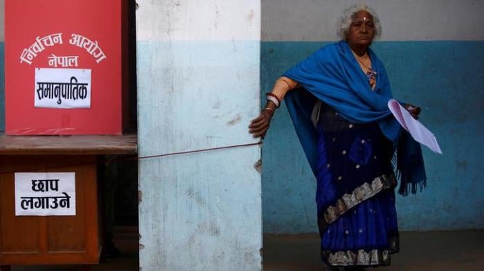 A woman walks to cast her vote during elections in Thimi, Nepal, December 7, 2017.