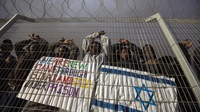 African migrants gesture behind a fence during a protest against Israel's detention policy towards them, at Holot, Israel's southern Negev desert detention centre February 17, 2014.