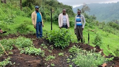 Men stand in front of burnt ground in Kenya's Mau forest.