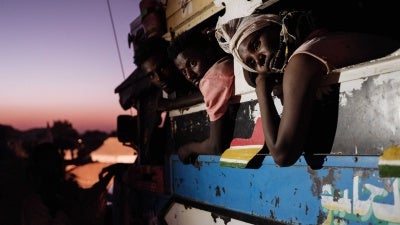 Men and women lean out of the windows of a bus