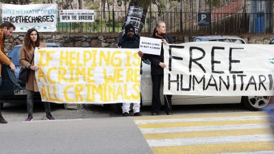 Protesters hold signs outside a Greek court in Mytilene