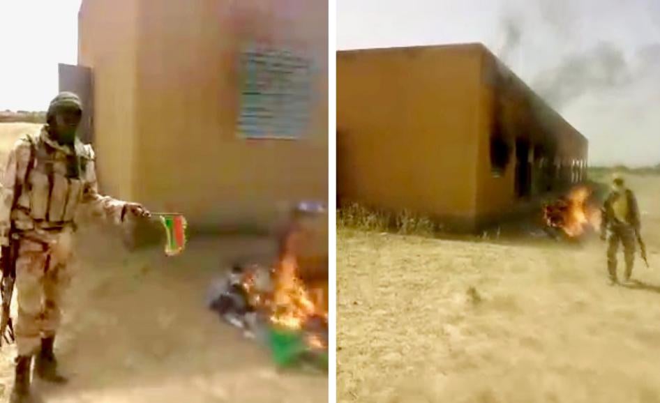 Armed men pose in front of a burning school building