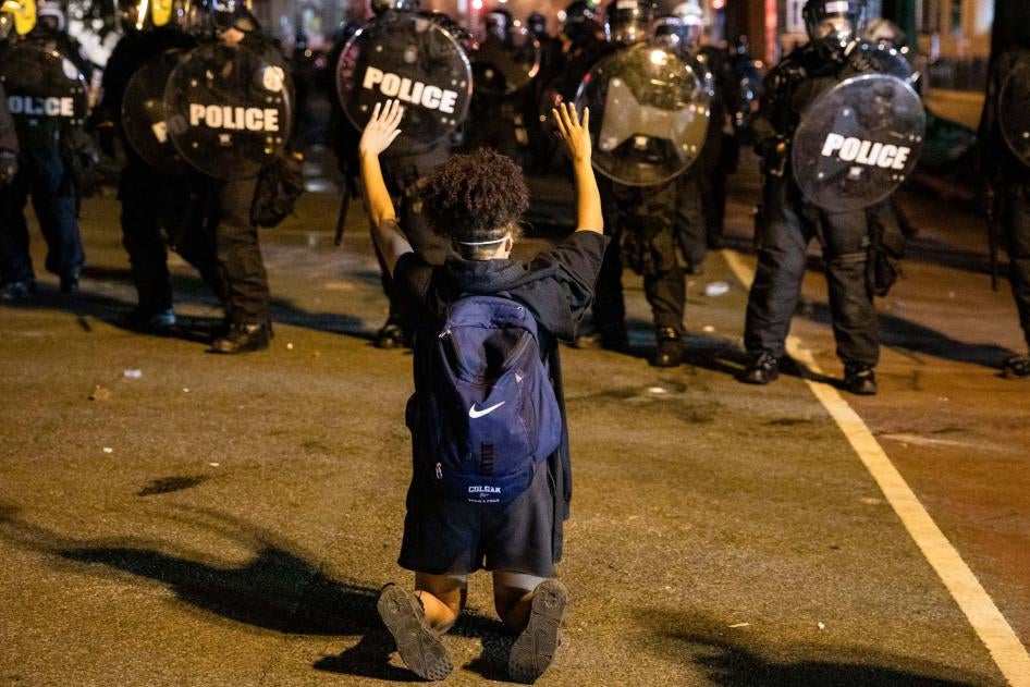 Un manifestant à genoux lève les bras, face à des policiers devant la Maison Blanche à Washington, le 31 mai 2020, six jours après le meurtre du Noir américain George Floyd par un policier à Minneapolis le 25 mai. Cet incident a déclenché une vague de manifestations à travers le pays.