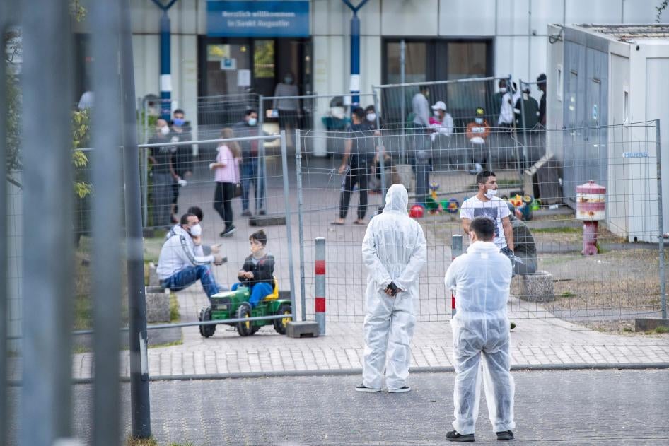 Mitarbeiter des Sicherheitsdiensts stehen in Schutzkleidung in einer Aufnahmeeinrichtung für Asylsuchende in Nordrhein-Westfalen in der 70 Menschen positiv auf das Coronavirus getestet wurden, 17. Mai, 2020.  © 2020 Marcel Kusch/picture-alliance/dpa/AP