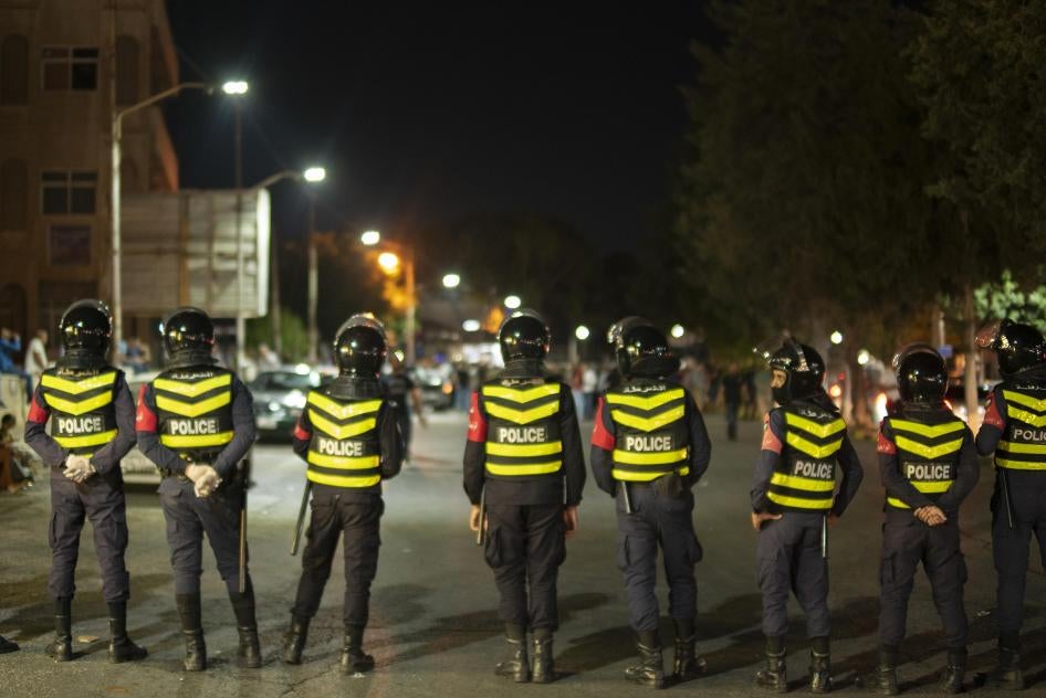  Jordanian police block a road in front of protestors in Irbid, north of Jordan on August 1, 2020.