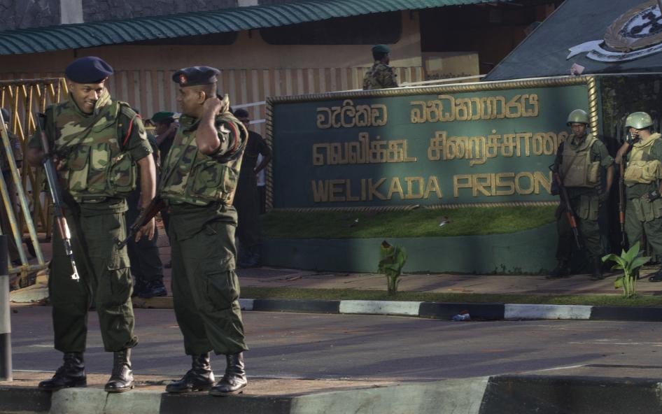 Armed soldiers stand in front of a building with a sign that reads "Welikada Prison"