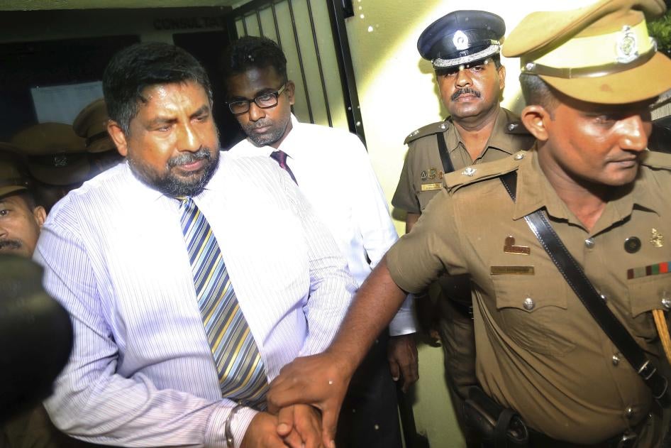 A policeman escorts a man in handcuffs