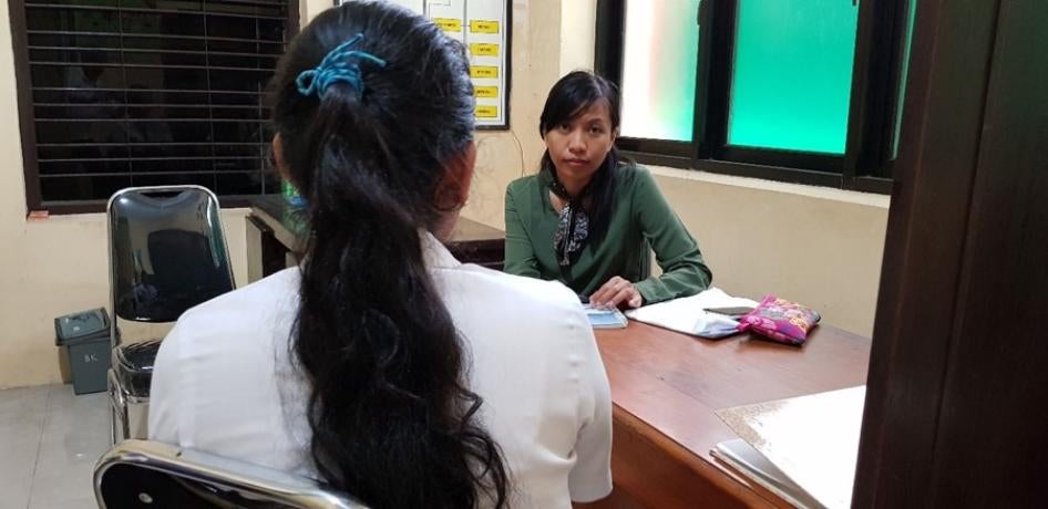 The back of the head of a seated girl being interviewed at a desk