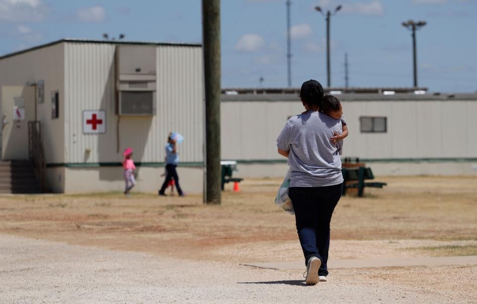 A woman walks carrying her child at the US Immigration and Customs Enforcement (ICE) South Texas Family Residential Center, in Dilley, Texas, August 23, 2019. 