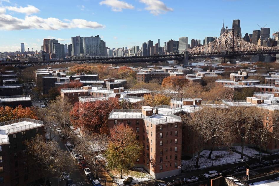 Aerial view of a housing complex with a city skyline behind it