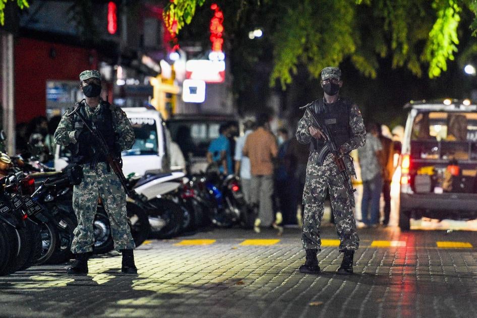 Armed police officers stand in a road