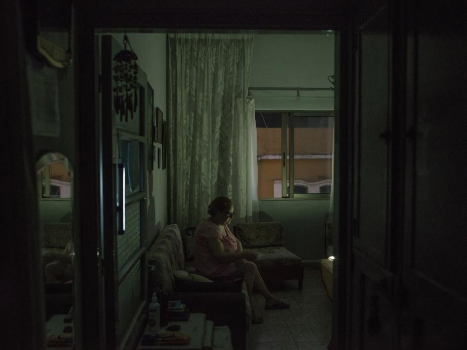 A woman uses chargeable lights in her living room during power cuts