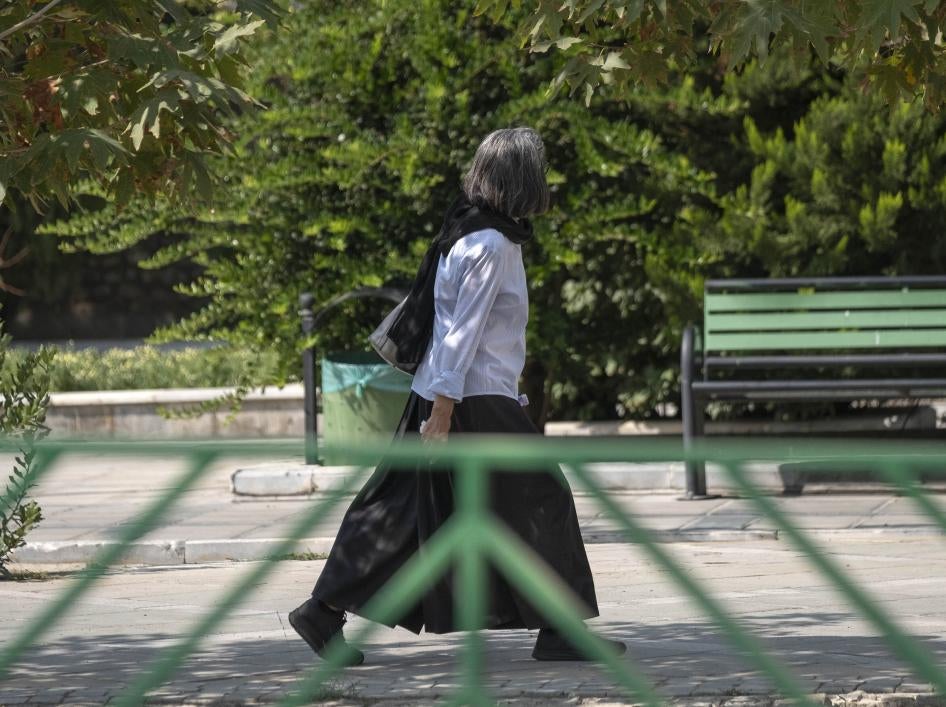 An Iranian woman walks along a street-side in Tehran without wearing her headscarf.