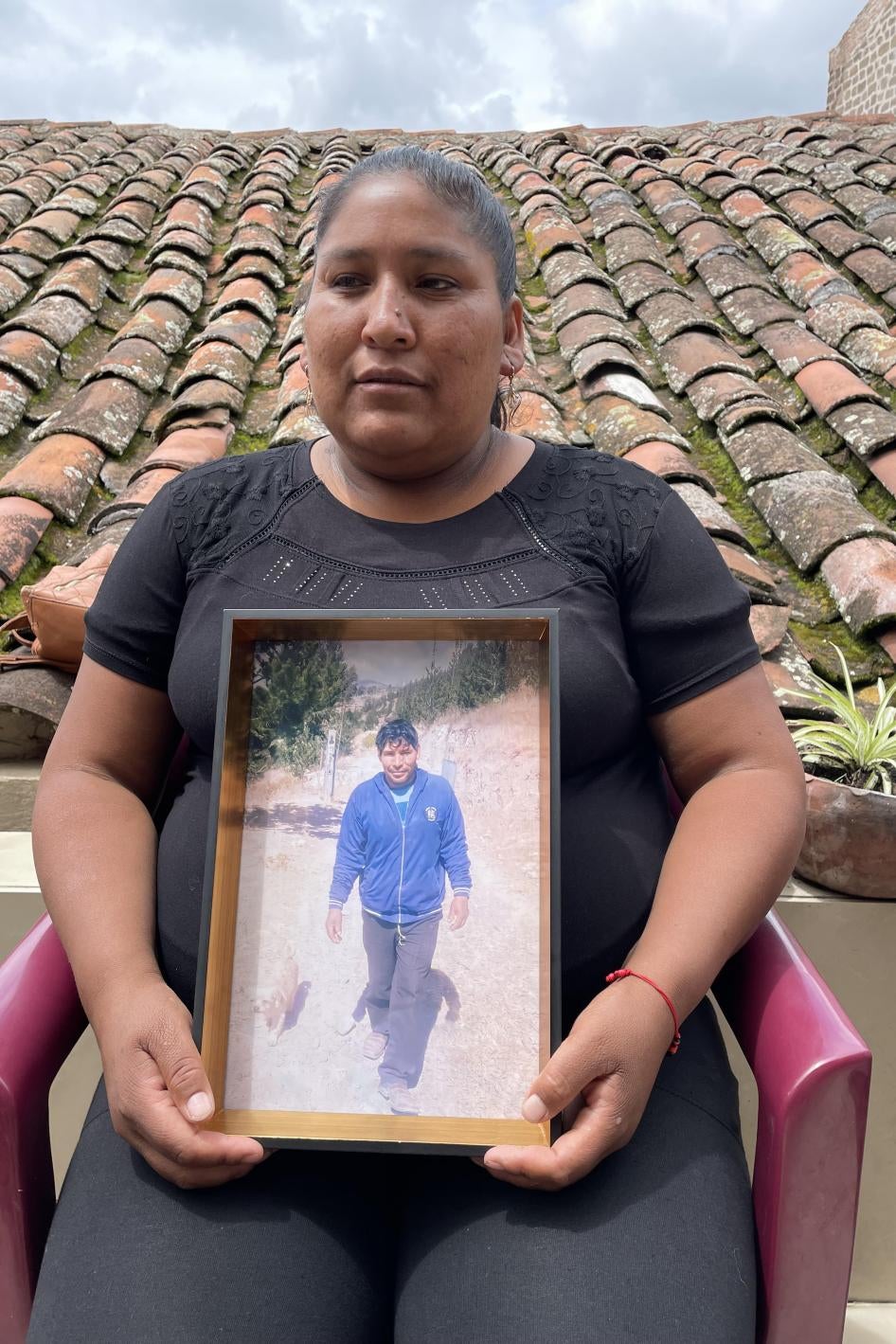 A seated woman holds a framed photo