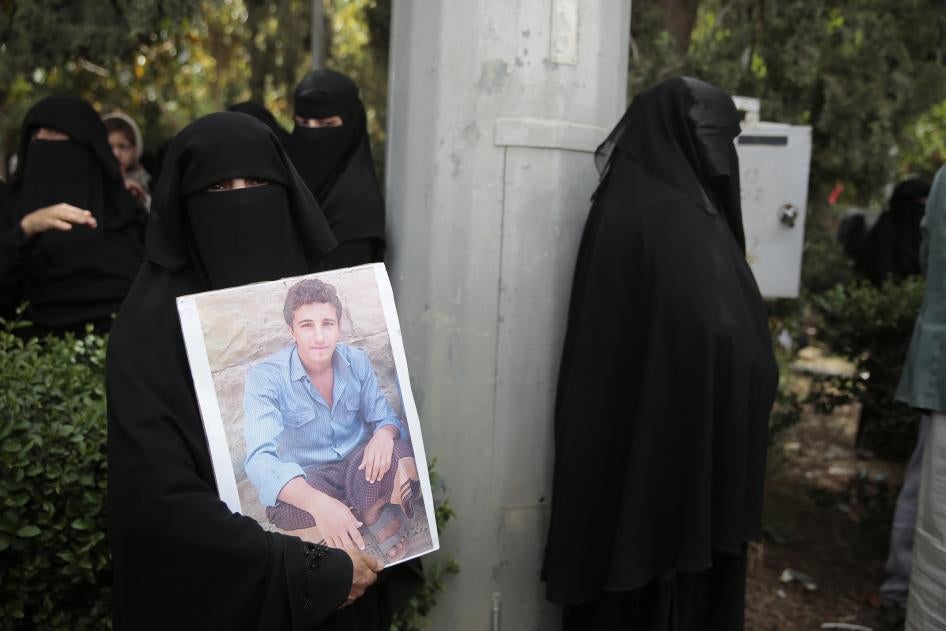 A woman holds her son's picture as she waits for Houthi prisoners to arrive at Sanaa airport, Yemen.