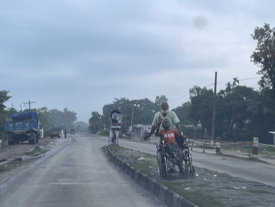A man pushes a child in a wheelchair on a street