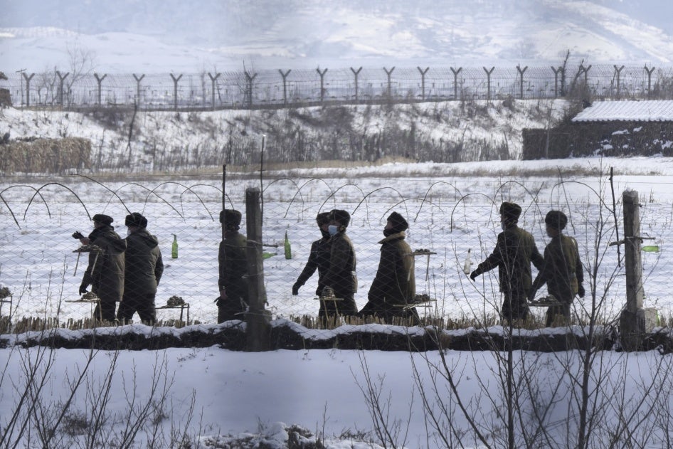 Des soldats nord-coréens patrouillaient au bord d'une rivière dans le comté d'Uiju, près de la frontière avec la Chine, le 22 décembre 2022 ; photo prise à Dandong, ville frontalière sur le territoire chinois.