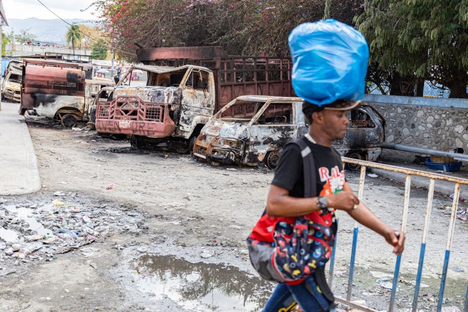 A man walks past several torched cars