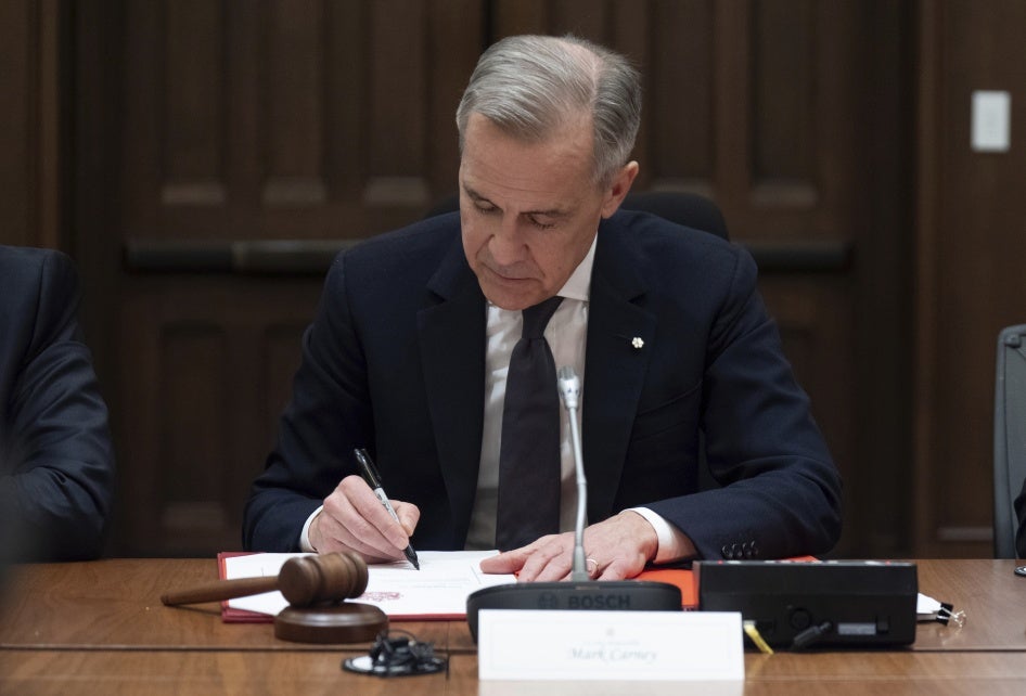 Canadian Prime Minister Mark Carney signs a document during cabinet meeting on Parliament Hill in Ottawa., March 14, 2025.