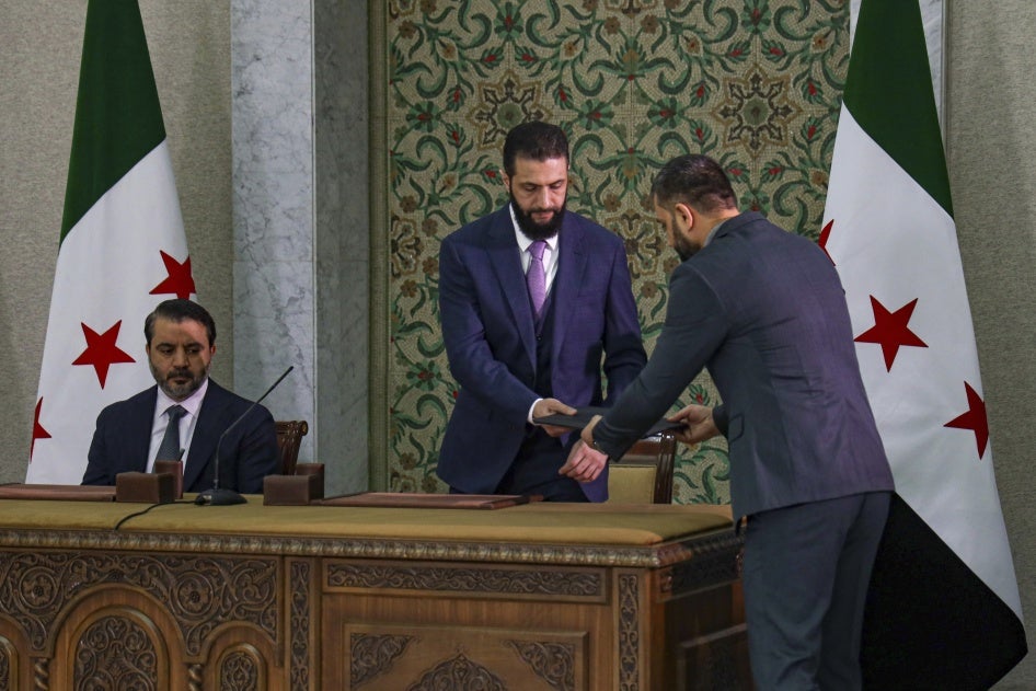 Syria's interim President Ahmad al-Sharaa, center, prepares to sign a constitutional declaration for Syria in Damascus, on March 13, 2025.
