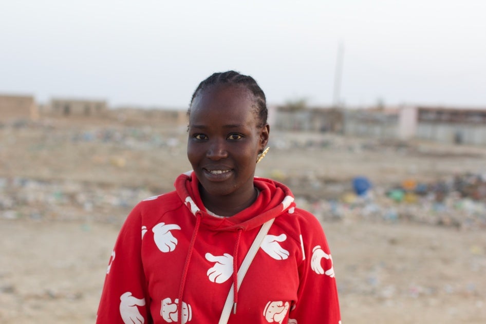 A woman in a red shirt standing in front of a waste dump