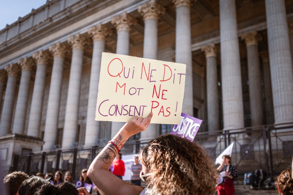Une personne brandissant une pancarte sur laquelle on peut lire « Qui ne dit mot ne consent pas » devant le Palais de Justice lors d'un rassemblement en soutien à toutes les victimes de violences sexuelles et sexistes à Lyon, France, le 19 octobre 2024. 