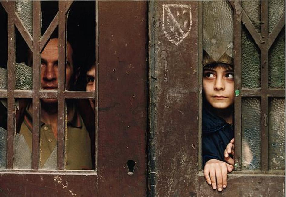 Photo 2A family peer out their front door which was damaged a few days earlier when a huge mortar bomb which killed at least 68 people crashed into a busy Sarajevo market. February 9, 1994.