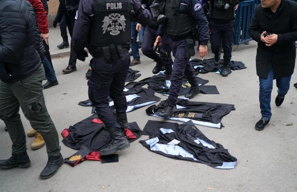 Turkish riot policemen walk over academic gowns laid down during a protest against the dismissal of academics from universities in the Cebeci campus of Ankara University