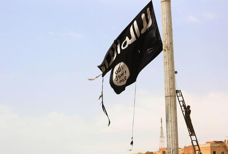 A member of the Syrian Democratic Forces removes an Islamic State flag in the town of Tabqa, west of Raqqa city, Syria, April 30, 2017. © 2017 Getty Images