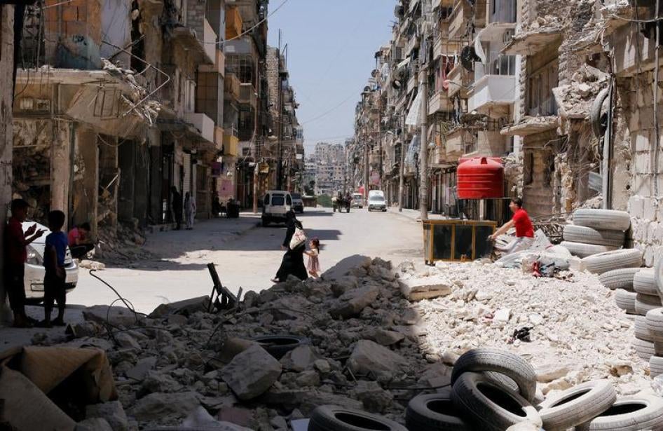 A woman walks with a child amid rubble at Bustan al-Qasr neighbourhood in Aleppo, Syria July 16, 2017.