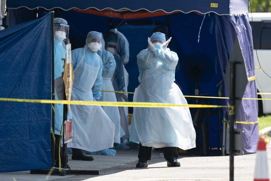A health worker in a protective suit gestures in a tent erected to test for the new coronavirus at a clinic in Kuala Lumpur, Malaysia, March 24, 2020.  