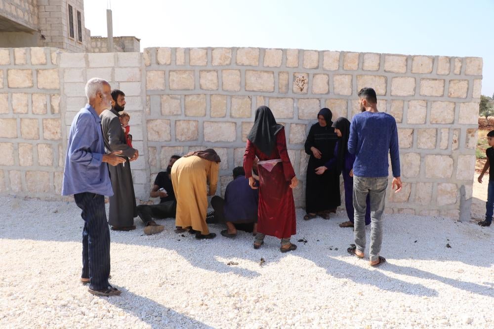 People gather around one of three people injured on October 7, 2023, after a nine-year-old picked up an unexploded submunition that detonated after he  dropped it the ground. The boy was severely injured, Termanin, Syria. 