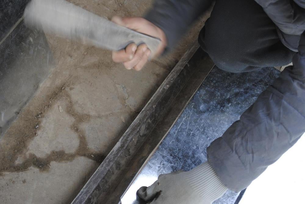 A young boy working at a metal workshop in Kabul hammers a metal sheet into a desired bend.    © 2016 Bethany Matta/Human Rights Watch.