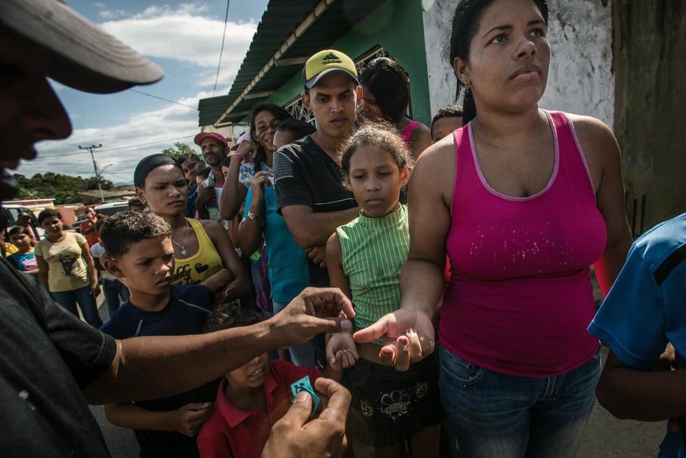 Un trabajador de una panadería distribuye números a una multitud de compradores, muchos de los cuales habían estado formando fila durante cinco horas, para poder comprar la ración de medio kilo de pan permitida, en Cumaná, 16 de junio de 2016. 
