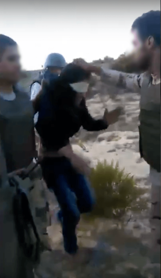 A member of a military-backed militia (R) holds a second detainee by his hair and interrogates him about his extended family. © 2017 Mekameleen