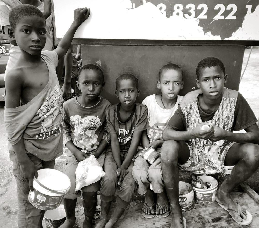 Un groupe de talibés âgés de 6 à 15 ans sont assis devant une boulangerie de Dakar au Sénégal, avec des petits seaux utilisés pour mendier. 