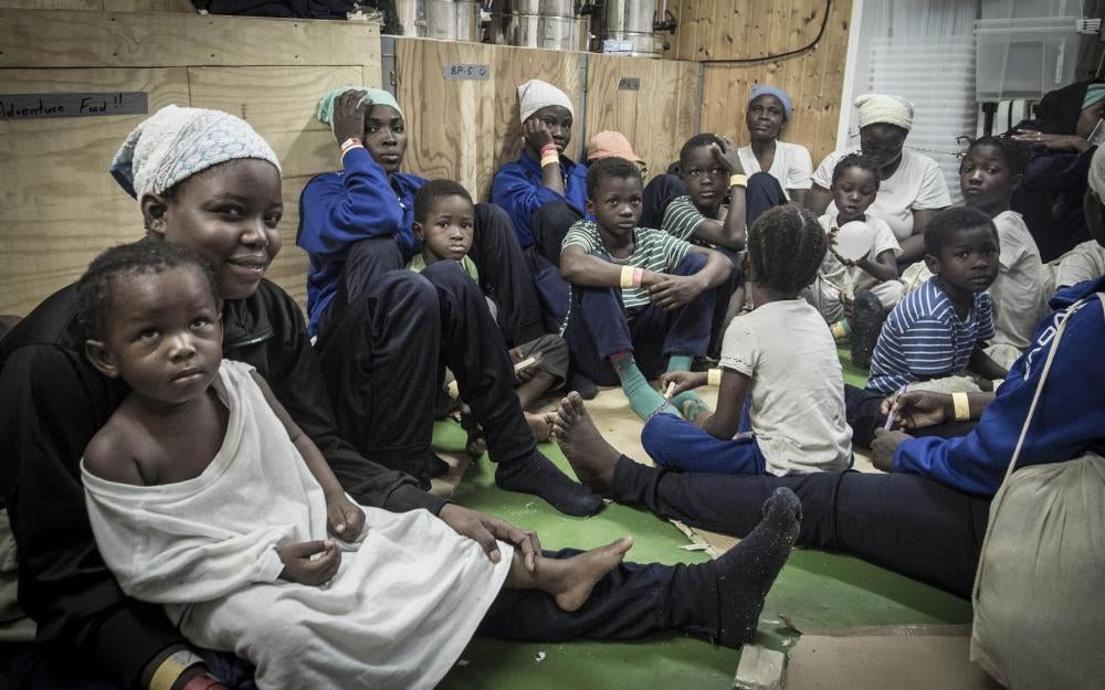 Women and children sit in the “green room,” an indoor space leading to the women’s shelter. October 13, 2017.