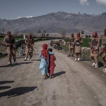 Two children walk by armed soldiers in the countryside