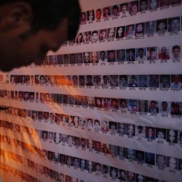 A man looks at a wall of portrait photos