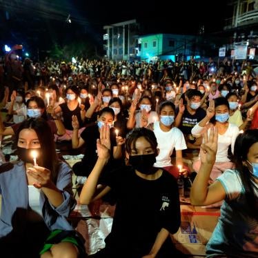 Protesters flash the three-fingered salute and hold candles during a rally at night in Yangon, Myanmar, March 14, 2021.