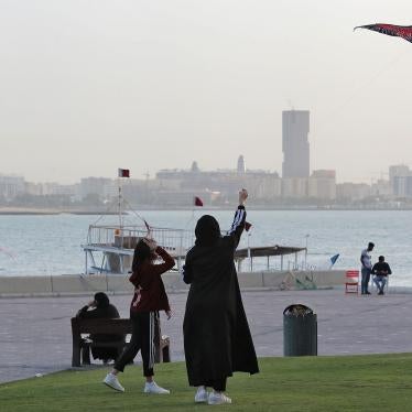 Women fly a kite in a park next to a body of water