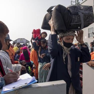An elderly man carries luggage over his head as he walks he off a ship