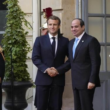 Two men in suits shake hands and pose for a photo