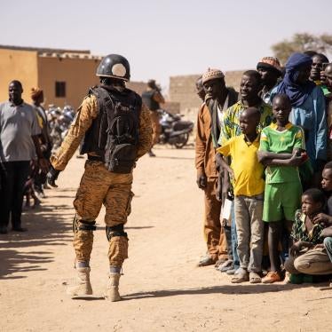 A government soldier walks past a group of villagers displaced by fighting in Burkina Faso’s northern Sahel region, February 3, 2020. 