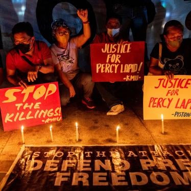 People light candles and hold signs during a rally