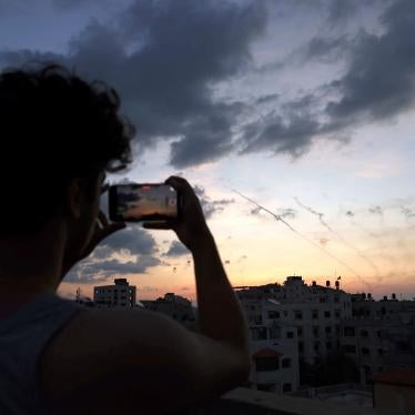 A man records a video with his mobile phone of rockets being fired