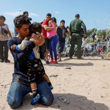 A migrant embraces his son after finishing the long journey to the US from Venezuela, in Eagle Pass, Texas, September 25, 2023. © 2023 Robert Gauthier/Los Angeles Times via Getty Images