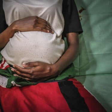 An unidentiable woman poses holding her baby bump