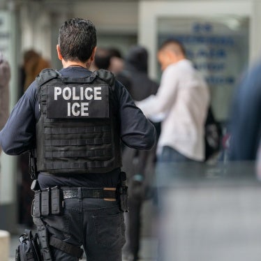 An ICE agent monitors hundreds of asylum seekers being processed upon entering the Jacob K. Javits Federal Building on June 6, 2023 in New York City.